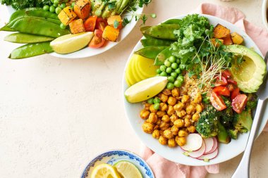 Avokado ve nohutlu sağlıklı vejetaryen yemek kaseleri kinoalı nohut ve mikro yeşillikle süslenmiş sebzeler ve taş zeminde fındık sosu.