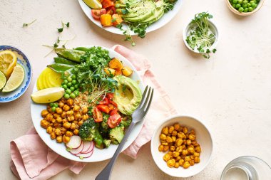 Avokado ve nohutlu sağlıklı vejetaryen yemek kaseleri kinoalı nohut ve mikro yeşillikle süslenmiş sebzeler ve taş zeminde fındık sosu.