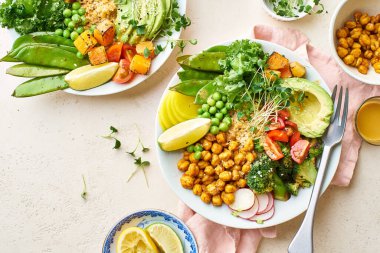 Avokado ve nohutlu sağlıklı vejetaryen yemek kaseleri kinoalı nohut ve mikro yeşillikle süslenmiş sebzeler ve taş zeminde fındık sosu.