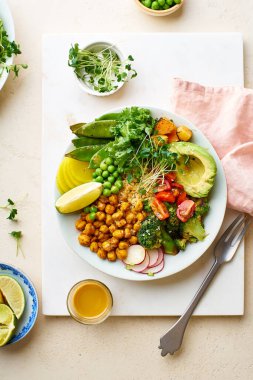 Avokado ve nohutlu sağlıklı vejetaryen yemek kasesi. Kinoalı ve sebzeli. Mikroyeşilliklerle süslenmiş.