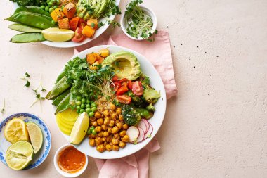 Avokado ve nohutlu sağlıklı vejetaryen yemek kaseleri kinoalı nohut ve mikro yeşillikle süslenmiş sebzeler ve taş zeminde fındık sosu.