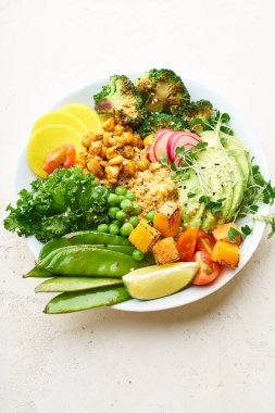 Avokado ve nohutlu sağlıklı vejetaryen yemek kasesi. Kinoalı ve sebzeli. Mikroyeşilliklerle süslenmiş.