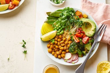 Avokado ve nohutlu sağlıklı vejetaryen yemek kasesi. Kinoalı ve sebzeli. Mikroyeşilliklerle süslenmiş.