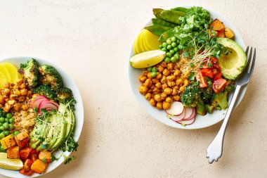 Avokado ve nohutlu sağlıklı vejetaryen yemek kaseleri kinoalı nohut ve mikro yeşillikle süslenmiş sebzeler ve taş zeminde fındık sosu.