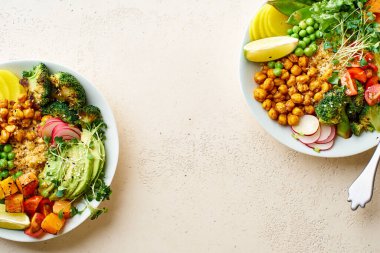 Avokado ve nohutlu sağlıklı vejetaryen yemek kaseleri kinoalı nohut ve mikro yeşillikle süslenmiş sebzeler ve taş zeminde fındık sosu.