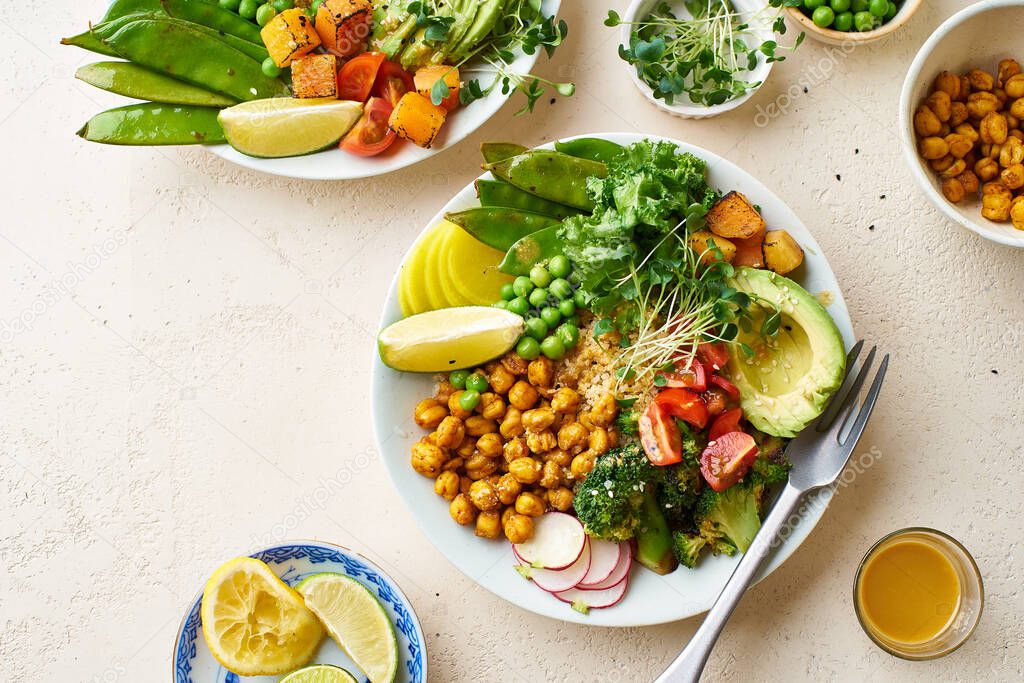 Healthy vegetarian lunch bowls with avocado and chickpeas with quinoa and vegetables garnished with microgreens and nut dressing  on stone background