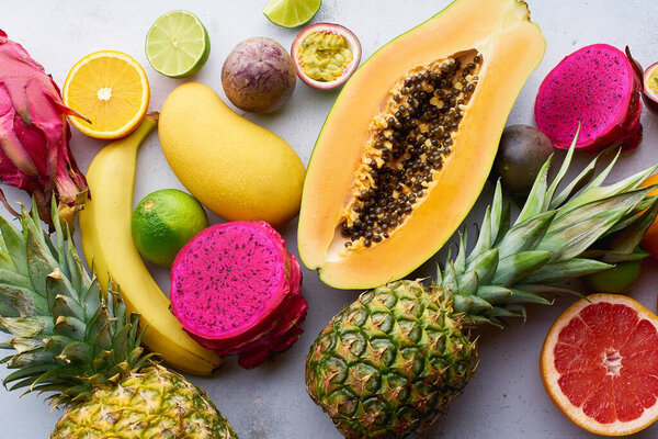 Healthy summer tropical exotic fruits on white table, top view 