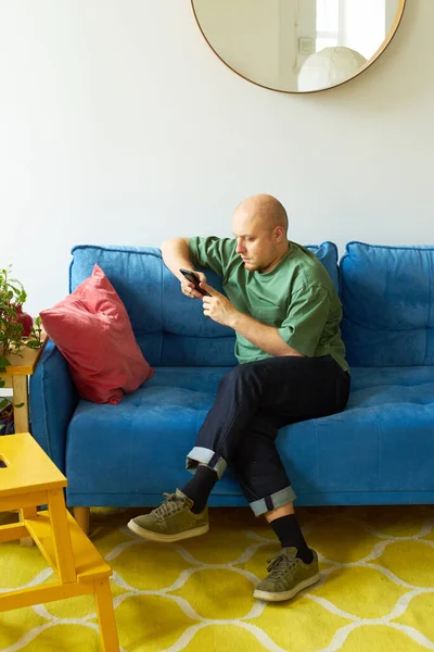 Homem Olhando Preocupado Usando Smartphone Enquanto Sentado Sofá Azul Sala — Fotografia de Stock