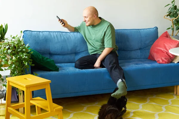 Homem Usando Smartphone Brincando Com Gato Enquanto Sentado Sofá Azul — Fotografia de Stock