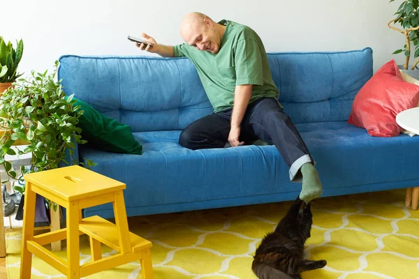 Homem Usando Smartphone Brincando Com Gato Enquanto Sentado Sofá Azul — Fotografia de Stock