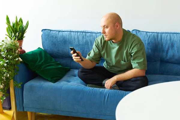 Mann Benutzt Smartphone Während Auf Blauem Sofa Wohnzimmer Sitzt — Stockfoto