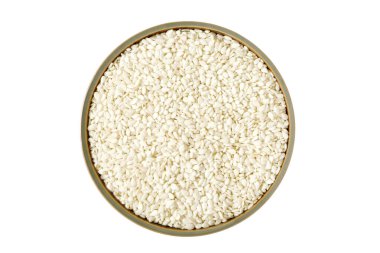 Üst görünüm susam tohumları beyaz arka planda sıralanmış bir kase içinde.