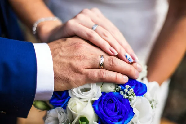 Newly wed couple\'s hands with wedding ring, white and blue roses