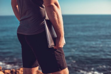 bir dizüstü bilgisayar deniz arka plan üzerinde tutan adam