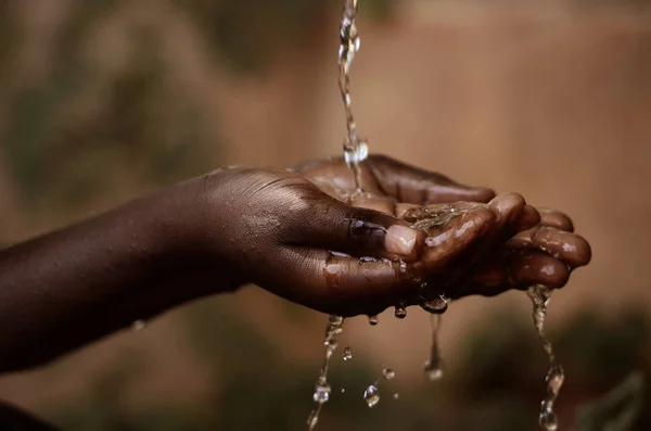 Handen van Afrikaanse kind vol water — Stockfoto