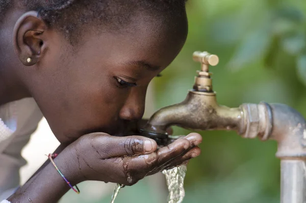 Afrikaanse jongen drinkwater uit de kraan — Stockfoto
