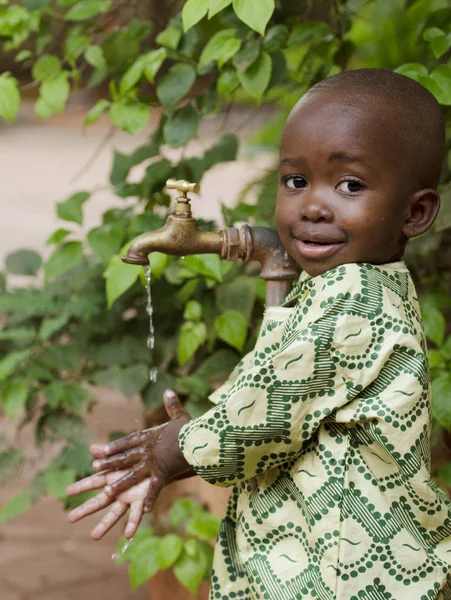 Afrikaanse jongen permanent in de buurt van kraan — Stockfoto