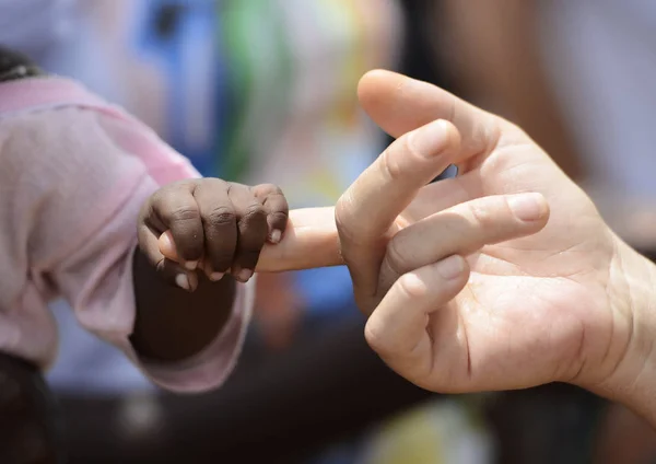 Mano africana sosteniendo dedo caucásico — Foto de Stock