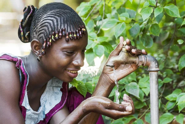 Afrikaanse meisje genieten van water uit de kraan — Stockfoto