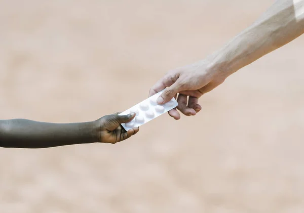 Hand giving medicine to child hand — Stock Photo, Image