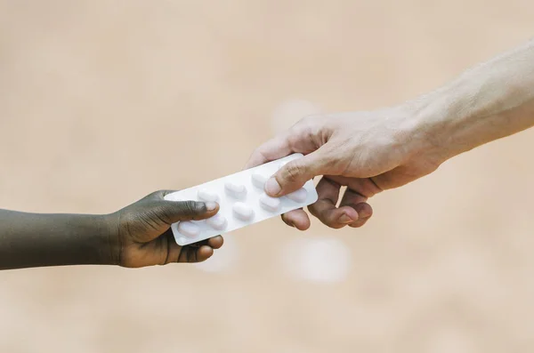Main donnant des médicaments à la main de l'enfant — Photo