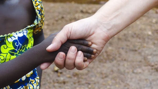 Mão caucasiana segurando mão criança africana — Fotografia de Stock