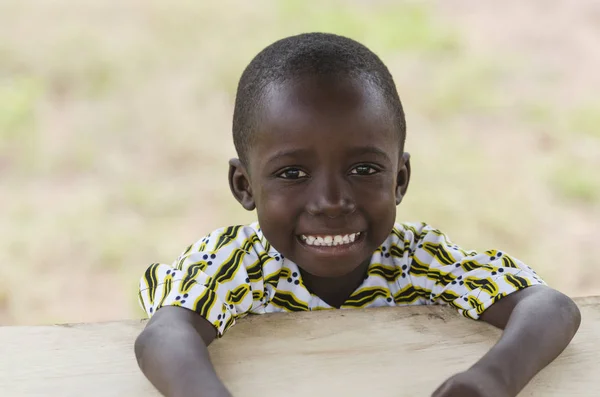 Niño sentado y sonriendo a la cámara — Foto de Stock