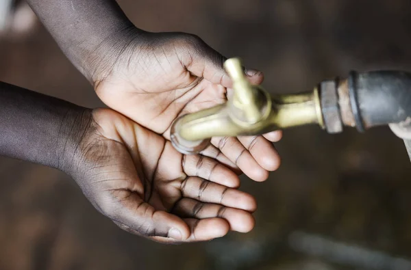 Mains de l'enfant africain sous robinet — Photo