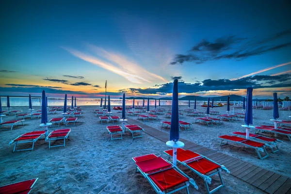 Closed umbrellas at sunset in Sardinia — Stock Photo, Image
