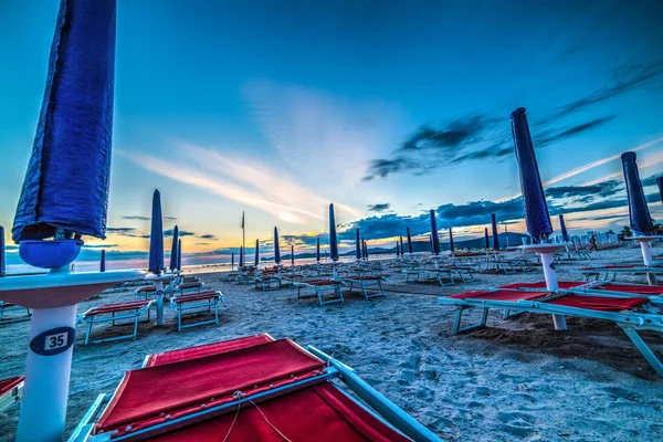 Sombrillas azules junto al mar al atardecer — Foto de Stock