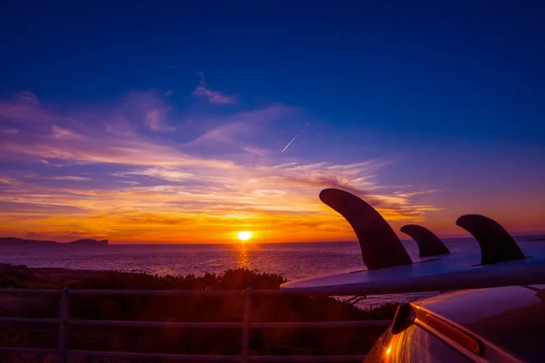 Auto met surfboard door de kust bij zonsondergang — Stockfoto