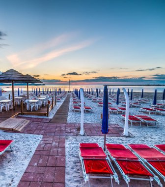 sandalye ve gün batımında deniz mavi şemsiye