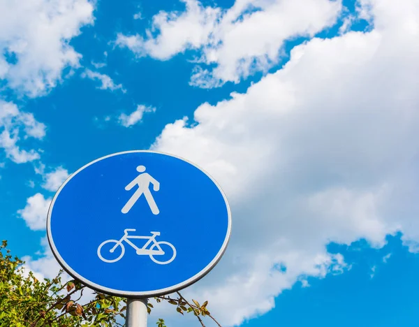 Voetgangers en fietsen teken onder een bewolkte hemel — Stockfoto