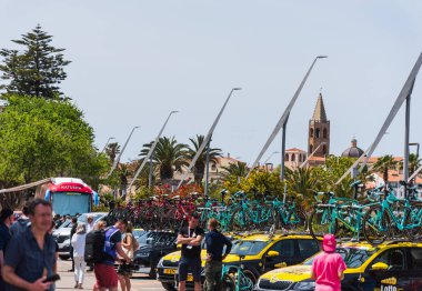 İtalya Bisiklet Turu ekip arabalarıyla Alghero çan kulesi arka planda