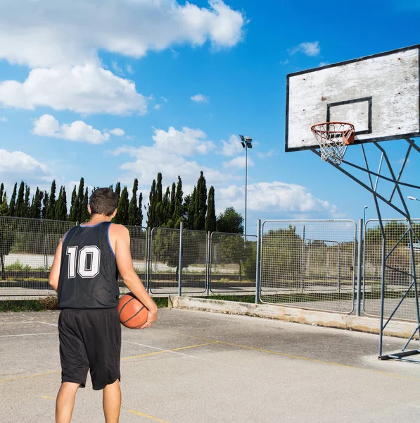 Jugador de baloncesto en un parque infantil bajo un cielo nublado — Foto de Stock