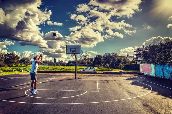 Jugador de baloncesto disparando bajo un sol brillante — Foto de Stock