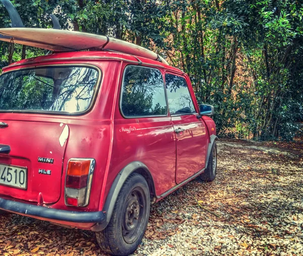 Back view of a red Mini Minor with a surfboard on the roof — Stock Photo, Image