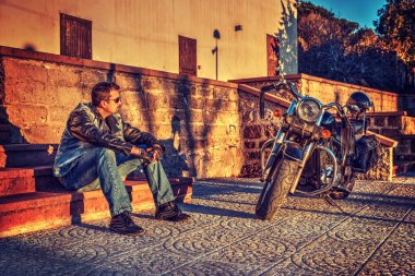 Günbatımında klasik motosiklet ve motorcu.