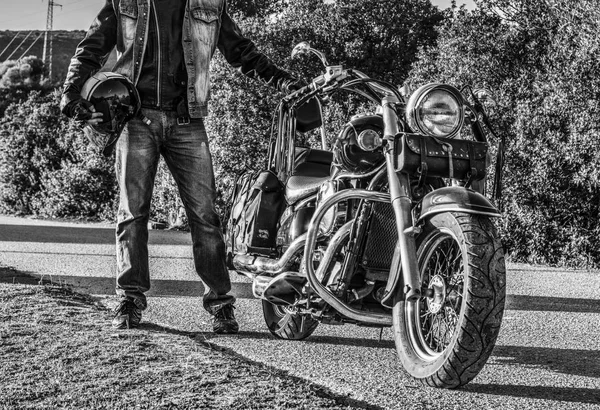 Biker steht neben einem klassischen Motorrad in schwarz-weiß — Stockfoto