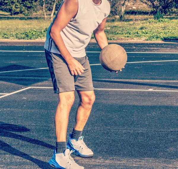 Вид спереди баскетболиста, держащего мяч на детской площадке — стоковое фото