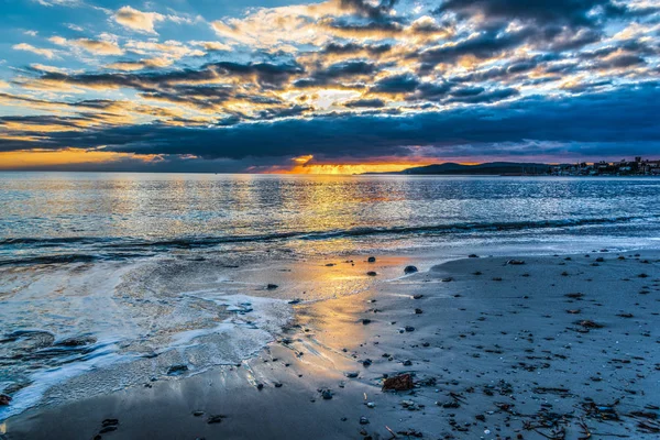 Písečné pobřeží pod zamračenou oblohou při západu slunce — Stock fotografie