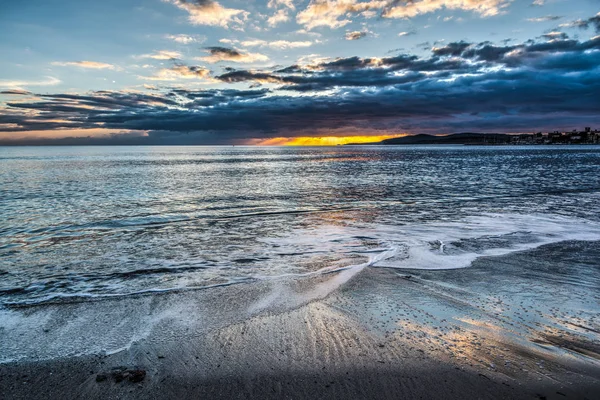 Nuvens escuras e sol brilhante sobre a costa de Alghero ao pôr do sol — Fotografia de Stock