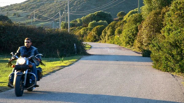Fietser op een klassieke motorfiets op een landweg — Stockfoto