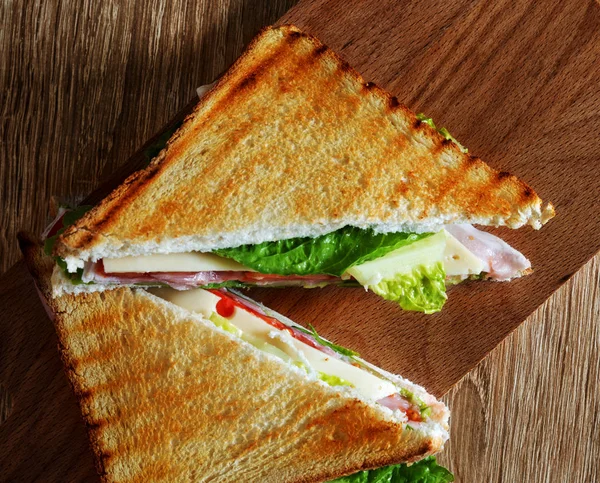 Mitades sándwich en una tabla de cortar de madera — Foto de Stock