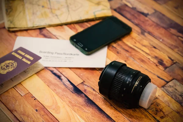 Kamera lensi, pasaport, uçak bileti, akıllı telefon, ahşap harita. — Stok fotoğraf