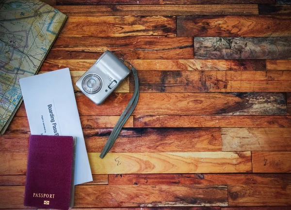 Διαβατήριο, κάρτα επιβίβασης, φωτογραφική μηχανή και χάρτης σε ξύλινο τραπέζι — Φωτογραφία Αρχείου