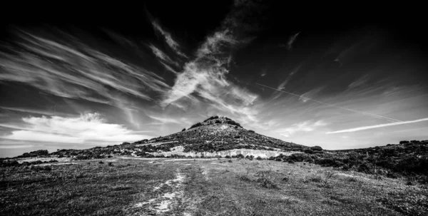 Маленький холм под облачным небом на Сардинии в черно-белом — стоковое фото