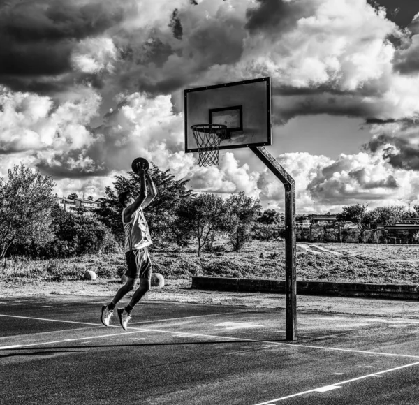 Jugador de baloncesto zurdo saltando al aro en blanco y negro — Foto de Stock