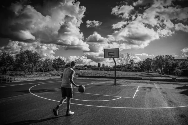 Jugador de baloncesto dribleando en un patio de recreo en blanco y negro —  Fotos de Stock