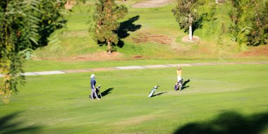 California 'da yeşil bir golf sahasında üç golfçü.